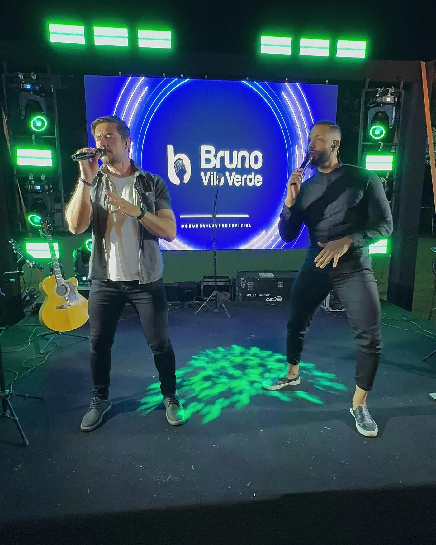 Palco com painel de LED e iluminação verde em show ao ar livre